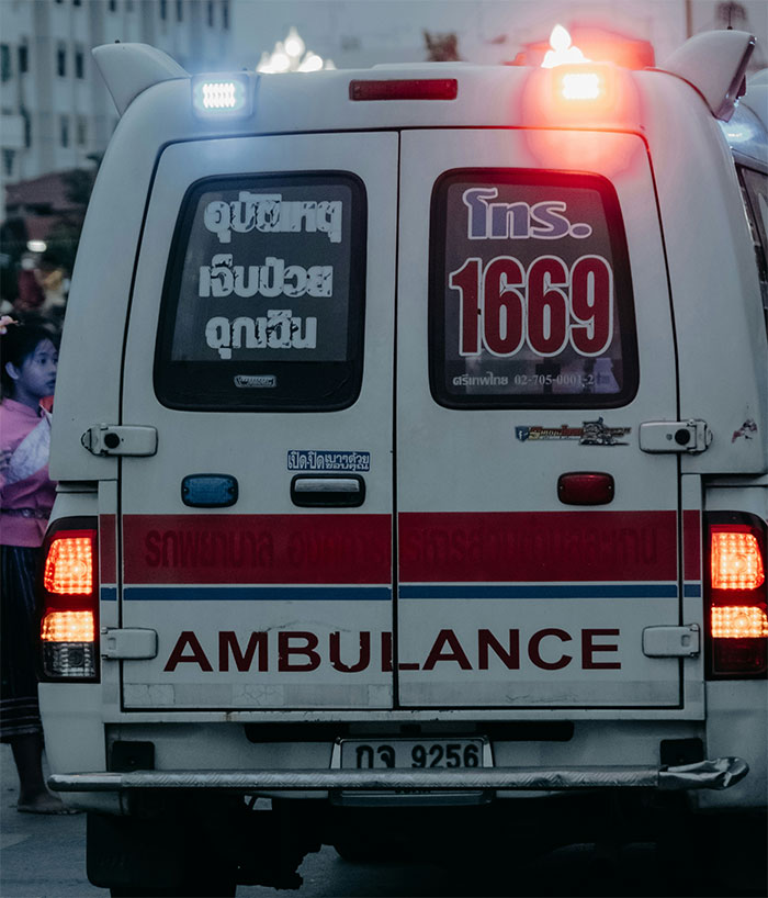Rear view of an ambulance with flashing lights arriving, highlighting a severe case of attention seeking at an office.