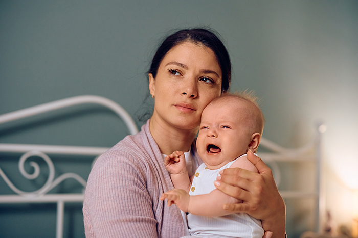Woman holding crying baby, refusing to give up life insurance policy amid family car refinancing dispute. Woman holding crying baby, refusing to give up life insurance policy amid family car refinancing dispute.