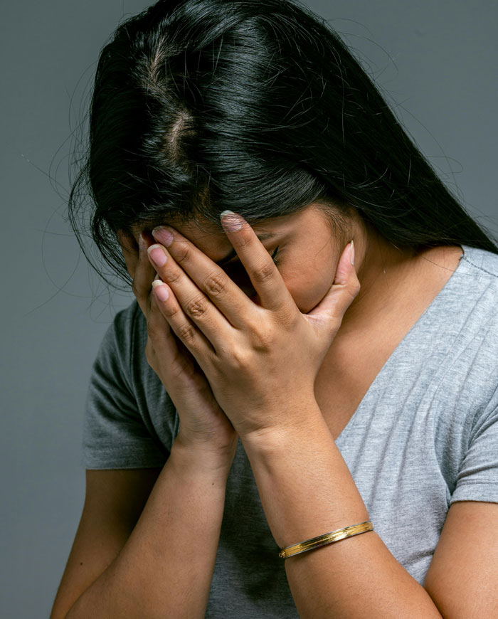 Woman covering her face with hands, expressing sadness over friendship of 10 plus years ended and lost good friend.