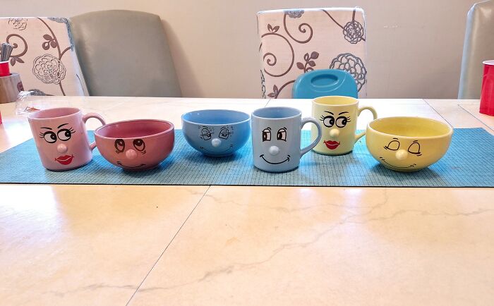Collection of thrifted cups and bowls featuring whimsical faces, showcasing weird and wonderful vintage finds on a dining table.