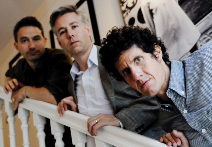 Three men leaning on a railing in a casual setting, illustrating celebrity encounters that went either well or badly.