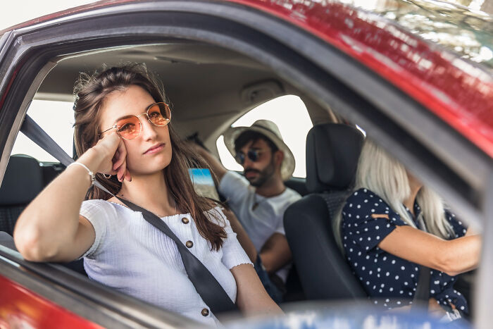 Young woman in a car looking bored and left out, capturing a moment that feels like being picked last in adult life.
