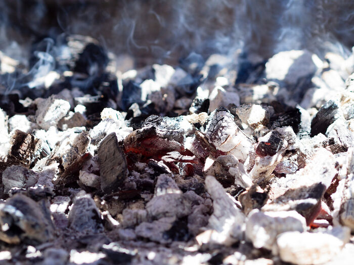 Close-up of smoldering hot embers with smoke rising, illustrating casual things that can actually be deadly.