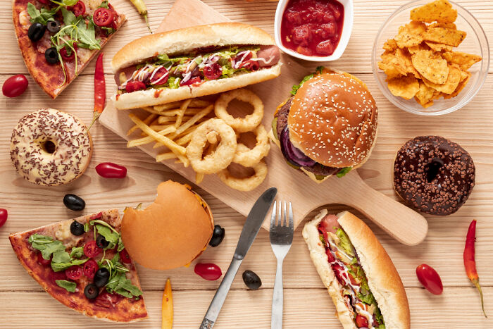 Assorted everyday items including burgers, hot dogs, pizza, donuts, and chips illustrating rising costs of common foods.