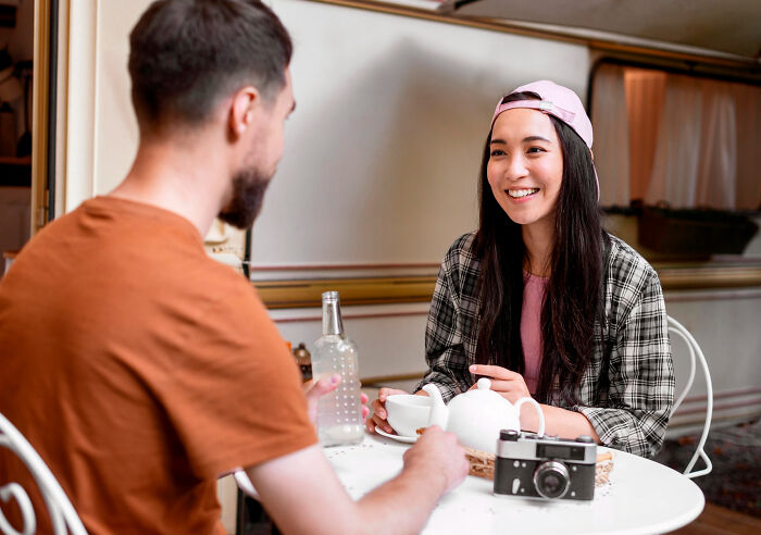Two people smiling and sharing a conversation over tea, reflecting on small decisions that changed their life forever.
