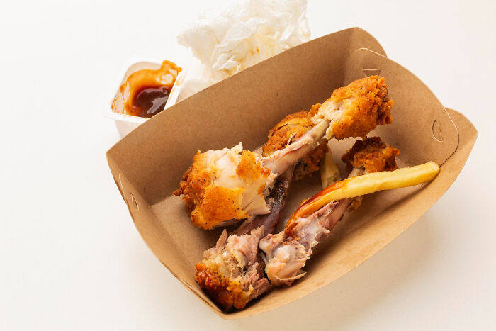 Partially eaten fried chicken and a French fry in a paper tray with sauce and napkins, illustrating wild cooking opinions.