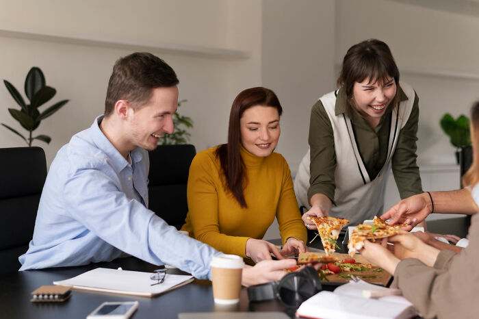 Group of adults sharing pizza at a casual meeting, capturing moments from an adult life that feel like gym class pick struggles.