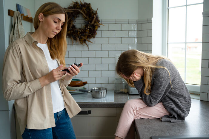 Young woman ignoring upset child in kitchen, illustrating soul-crushing things parents said to them in difficult moments.