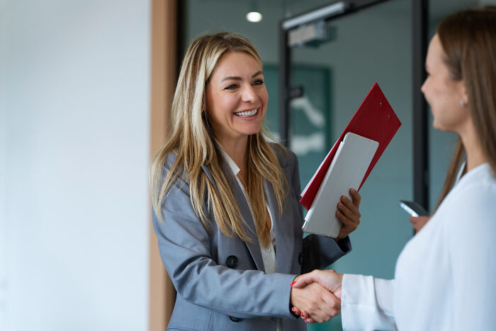 Two professional women shaking hands in an office, symbolizing a small decision that changed life unexpectedly.