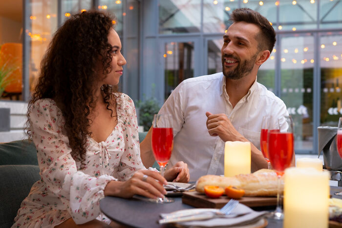Couple enjoying drinks and conversation at a cozy outdoor table, representing small decisions that change life.