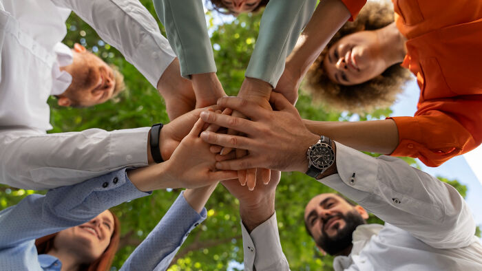 Group of diverse adults joining hands outdoors symbolizing moments that feel like being picked last in gym class.