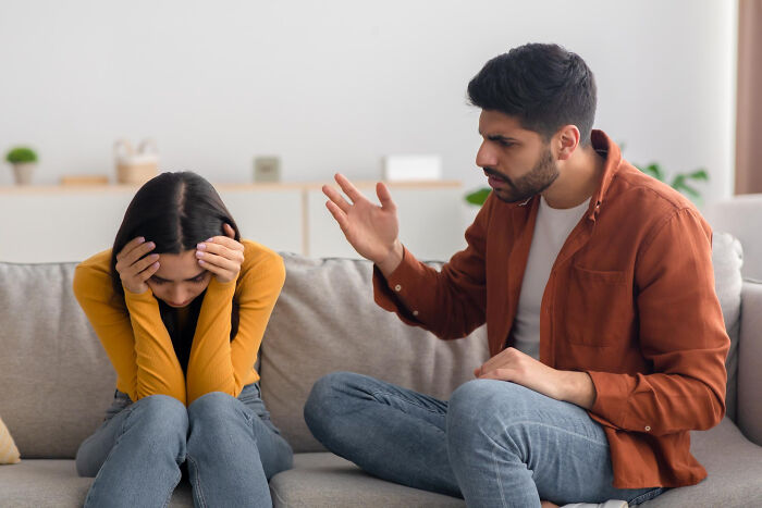 A young woman showing distress while a man speaks angrily, illustrating soul-crushing things parents told them.