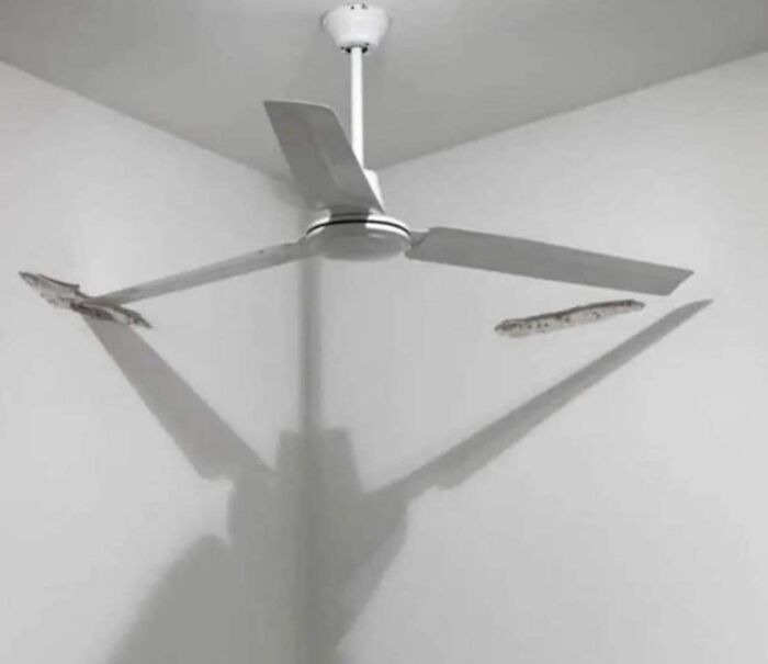 Ceiling fan with broken blades casting sharp shadow on wall, showing a failed renovation effort and saving mistake.