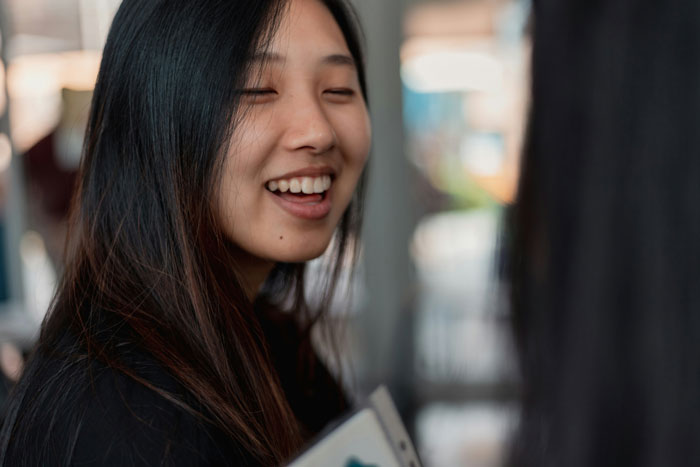 Young woman smiling and talking indoors, illustrating common problematic behaviors women get a pass for according to men.