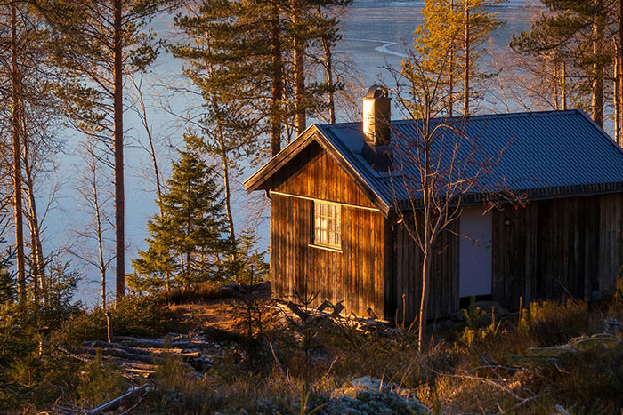Wooden cabin in forest near lake at sunset, evoking a scary gut feeling to leave now experience.
