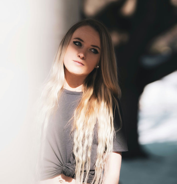 Young woman with long blonde hair looking thoughtful, reflecting on the reason for losing a good friend.