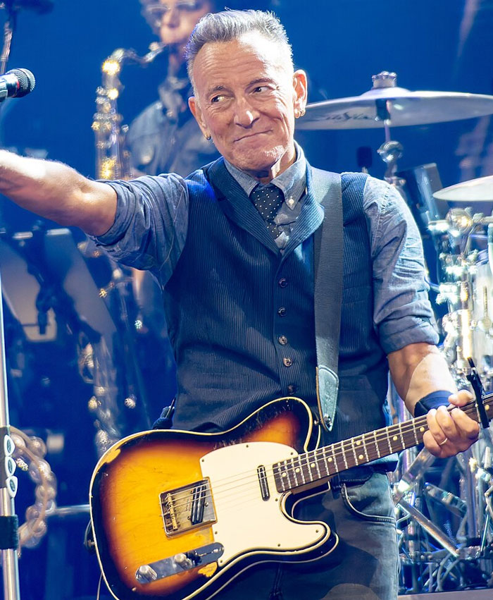 Male musician playing guitar on stage during a live concert, capturing a memorable celebrity encounter moment.