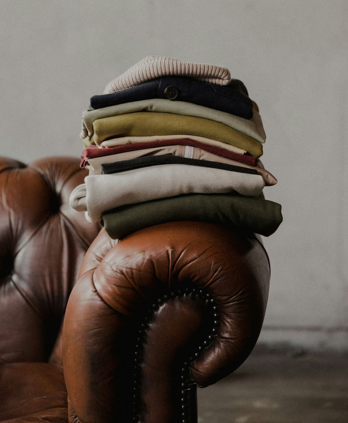 Stack of folded clothes on a brown leather chair representing one weird rule parents had that seemed normal until older.