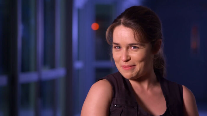 Actress in a dark setting, smiling subtly while discussing miscast actors in popular movies and their impact.