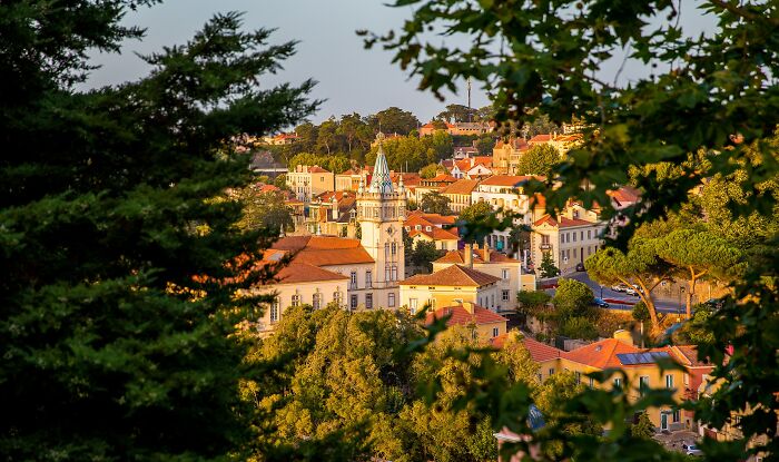 Scenic view of a hidden UNESCO gem town with historic buildings and lush greenery in golden sunlight.