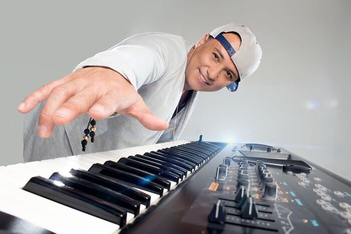 Man in a backward cap playing keyboard, representing cringey nineties fashions and nostalgic music style.
