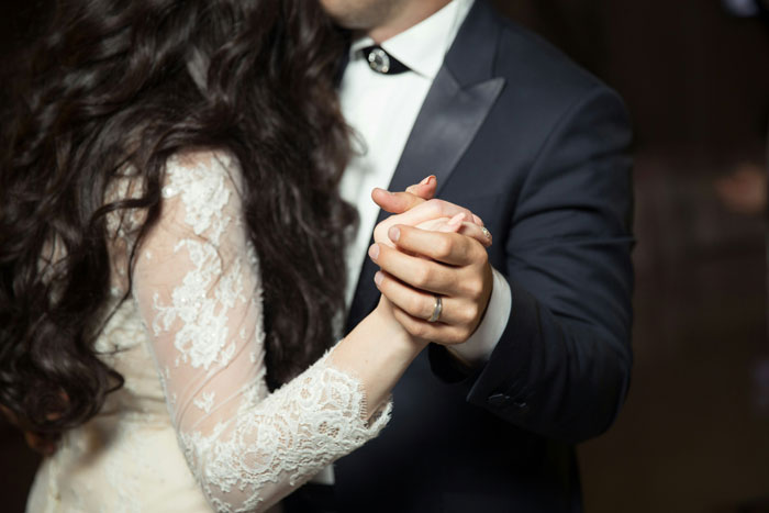 Couple holding hands and dancing closely, representing trust and secrets between spouses after marriage.