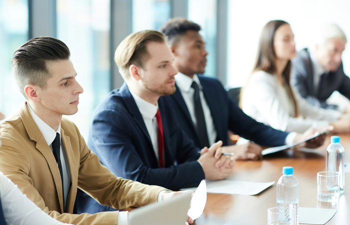 Group of young professionals listening intently during a meeting, symbolizing people who escaped from cults sharing experiences.