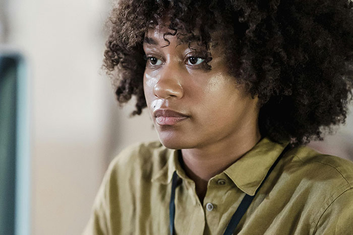 Young woman with curly hair looking serious, reflecting on a scary gut feeling about needing to leave immediately.