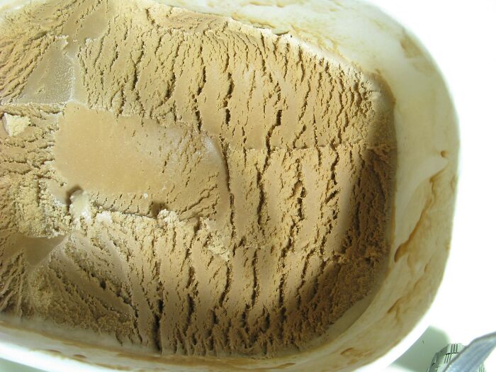 Partially eaten tub of ice cream with texture marks, illustrating an example of excessive laziness shared by people.