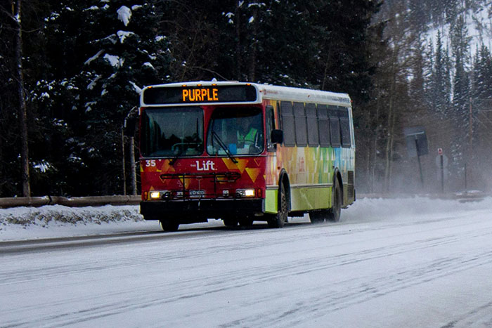 Public transit bus driving on a snowy road surrounded by trees, illustrating a gut feeling to leave now scenario.
