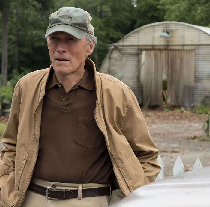 Elderly man in casual outfit and cap outdoors near rustic building, illustrating celebrity encounters that went well or bad.
