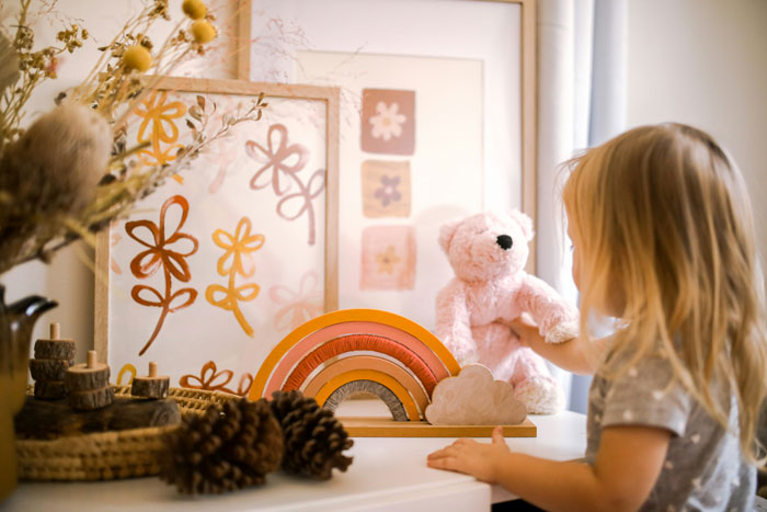 Child playing with teddy bear and toys in a cozy room, illustrating weird rules parents had many thought were normal.