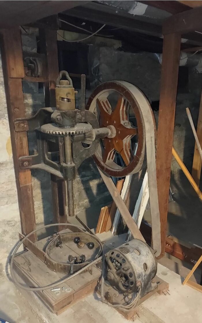 Rusty mechanical device with large gear wheel in dim basement, a strange thing found in homes with hidden or haunted pasts.