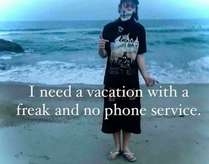Person wearing a graphic t-shirt and mask standing on beach with waves in background in cute and wholesome posts.