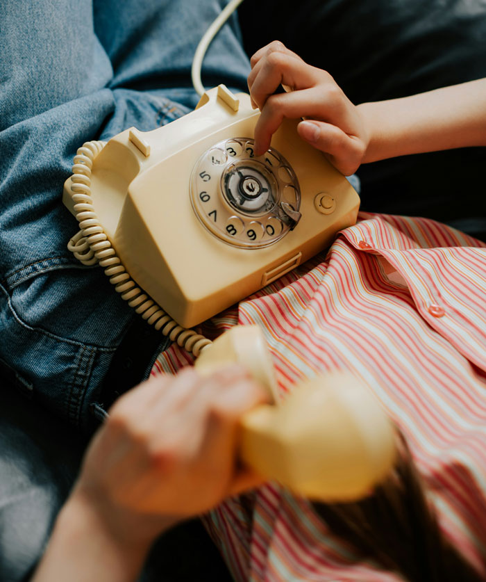 Child dialing a vintage rotary phone while holding the receiver, illustrating one weird rule parents had growing up.
