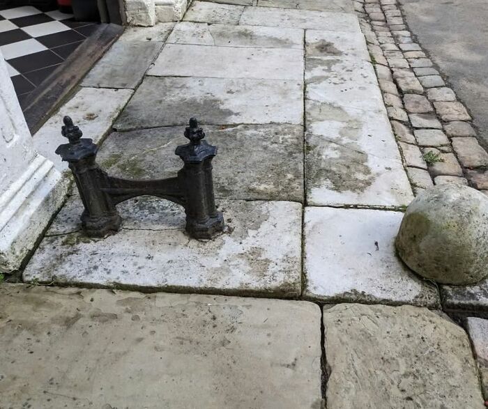 Old iron boot scraper on worn stone pavement in a home with hidden and haunted pasts.
