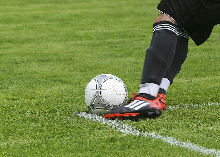 Soccer player wearing cleats about to kick a ball on green grass, illustrating entertaining facts shared in a sports thread.