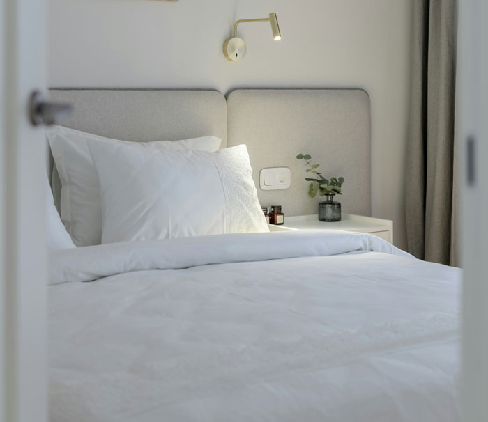 Neatly made bed with white linens and pillows in a minimalistic bedroom, highlighting unusual parent rules.