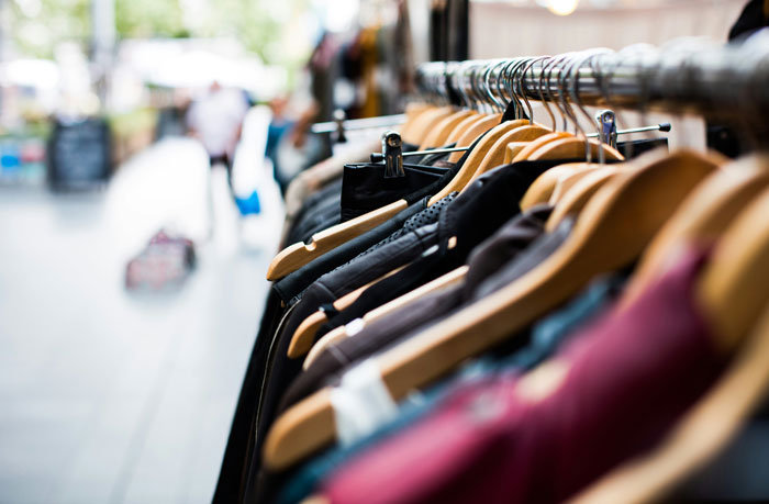 Clothing on wooden hangers displayed outside a store, illustrating habits linked to being raised poor.