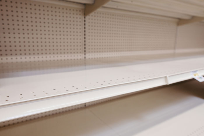 Empty store shelves with no products, illustrating effects of manager decisions on staff and sales performance.