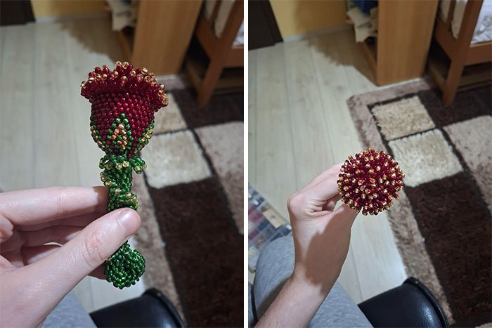 Hand holding a detailed crochet beaded flower with red and green beads, showcasing crochet masterpieces.