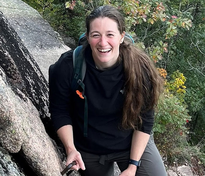 Smiling woman hiking outdoors near rocks and trees, related to army pilot moments before horrific DC plane crash.