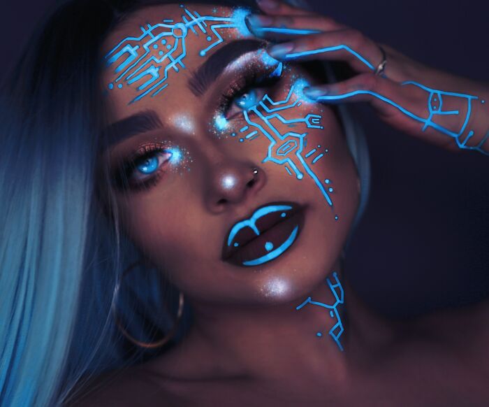 Close-up of a woman with glowing blue circuit-inspired makeup and glittery eyeshadow showcasing incredible makeup looks.