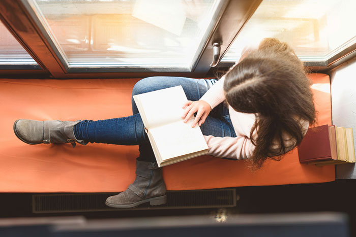Woman reading a book by a window, illustrating moments when bosses, teachers, or parents went completely off the rails.