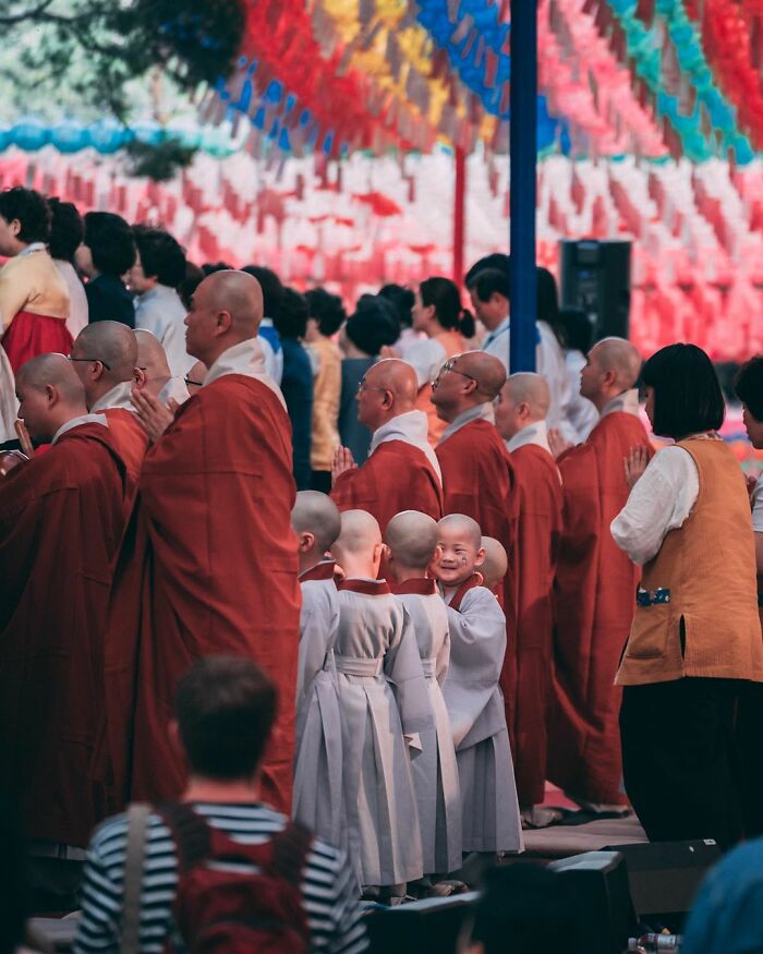Group of monks and children in robes during a colorful street photography moment in a public gathering.