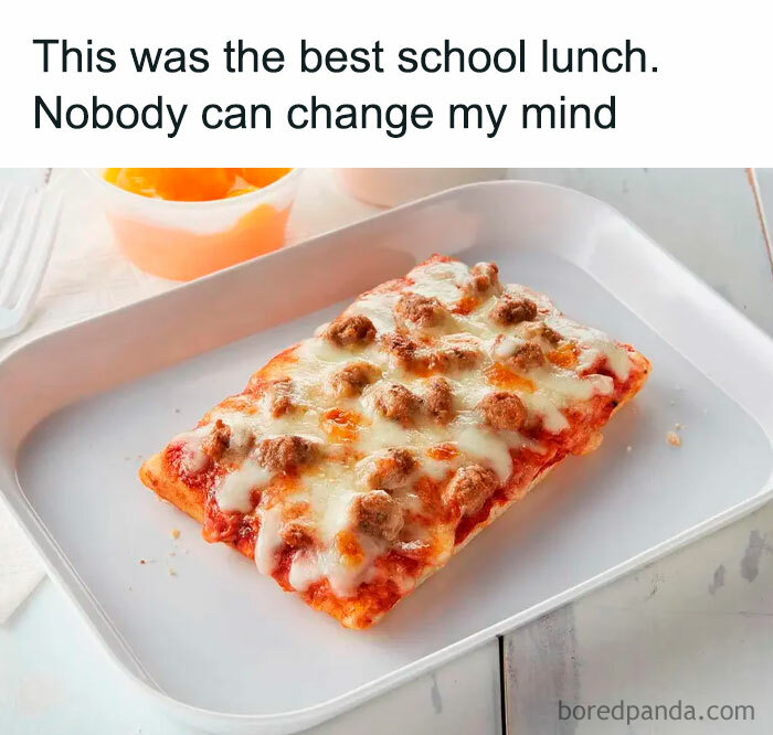 School lunch nostalgic pic showing a slice of pizza with melted cheese and sausage on a white tray.