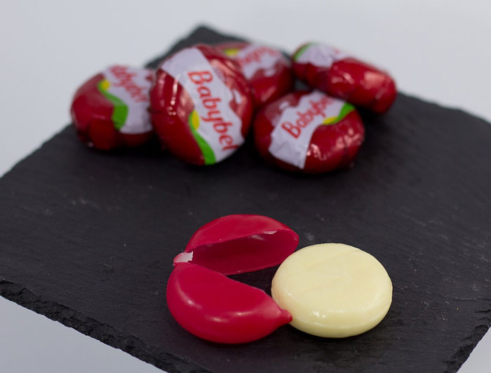 Babybel cheese with red wax coating partially removed, illustrating a weird habit related to being raised poor.