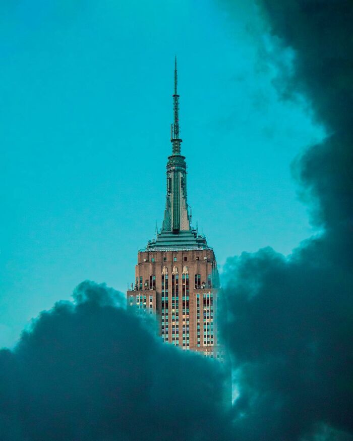 Empire State Building emerging through surreal clouds in a creative photo edit showcasing good visual lies by a Swedish artist.