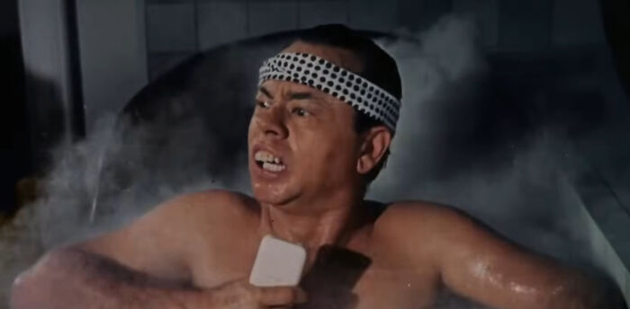 Actor wearing a white headband with black dots, holding a bar of soap, in a tense movie scene showcasing miscast actors.