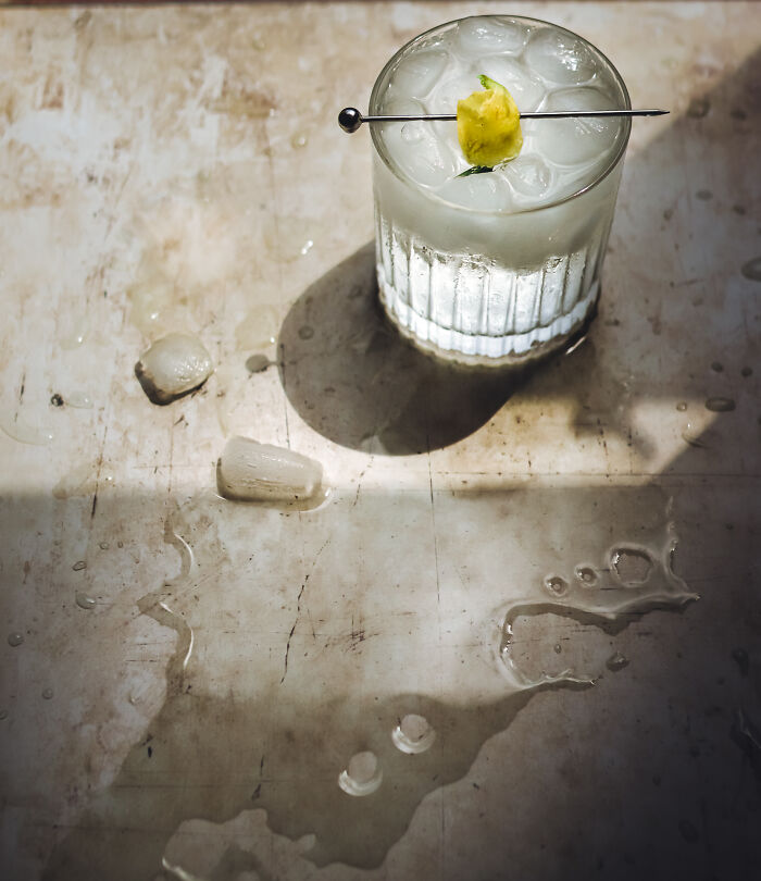 Glass of iced cocktail with pineapple garnish on wet rustic surface, a stunning food photography shot from 2025 awards.